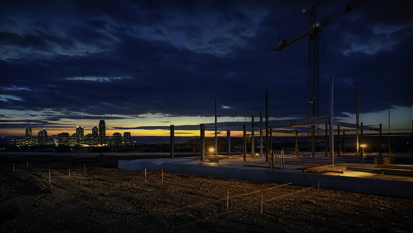 A construction site at blue hour with the skyline behind